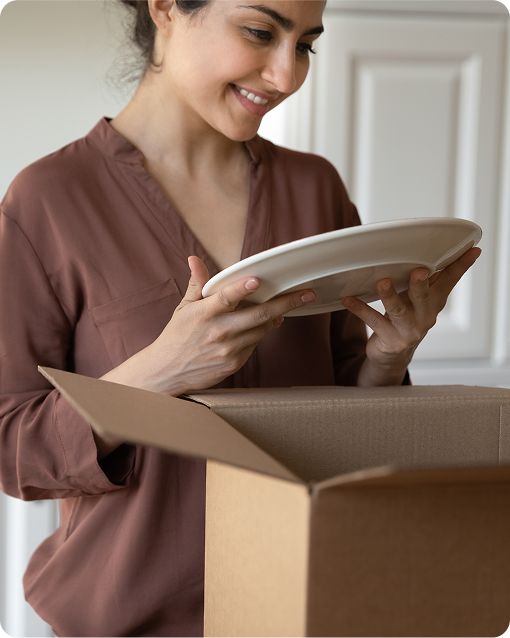 Woman unpacking fragile plate from moving box after relocation