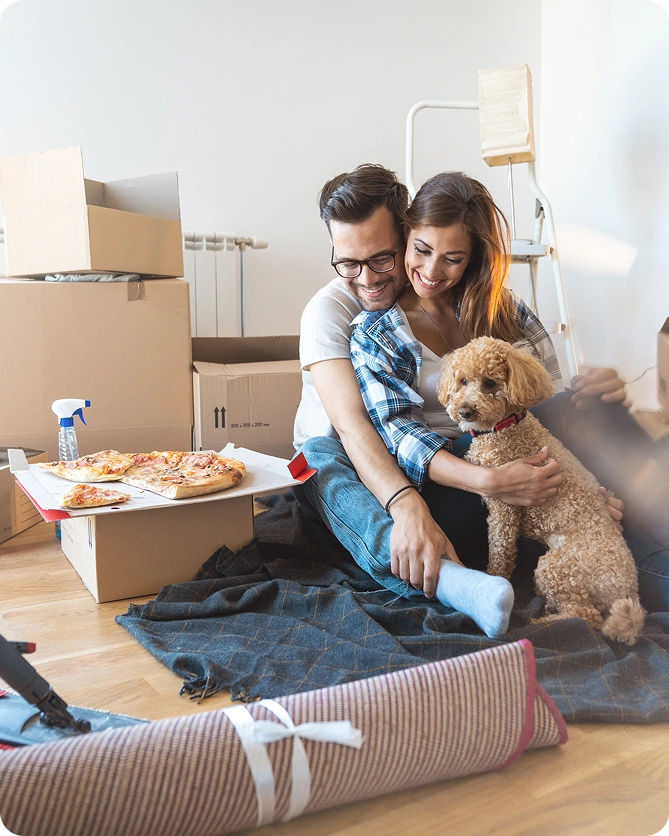 Couple relaxing with dog among moving boxes in their new home