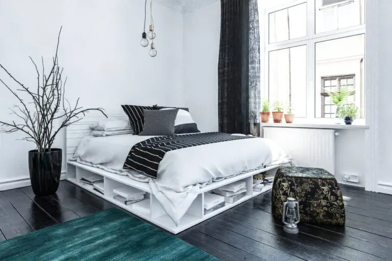 Modern Scandinavian bedroom with white pallet bed frame and dark wood floor