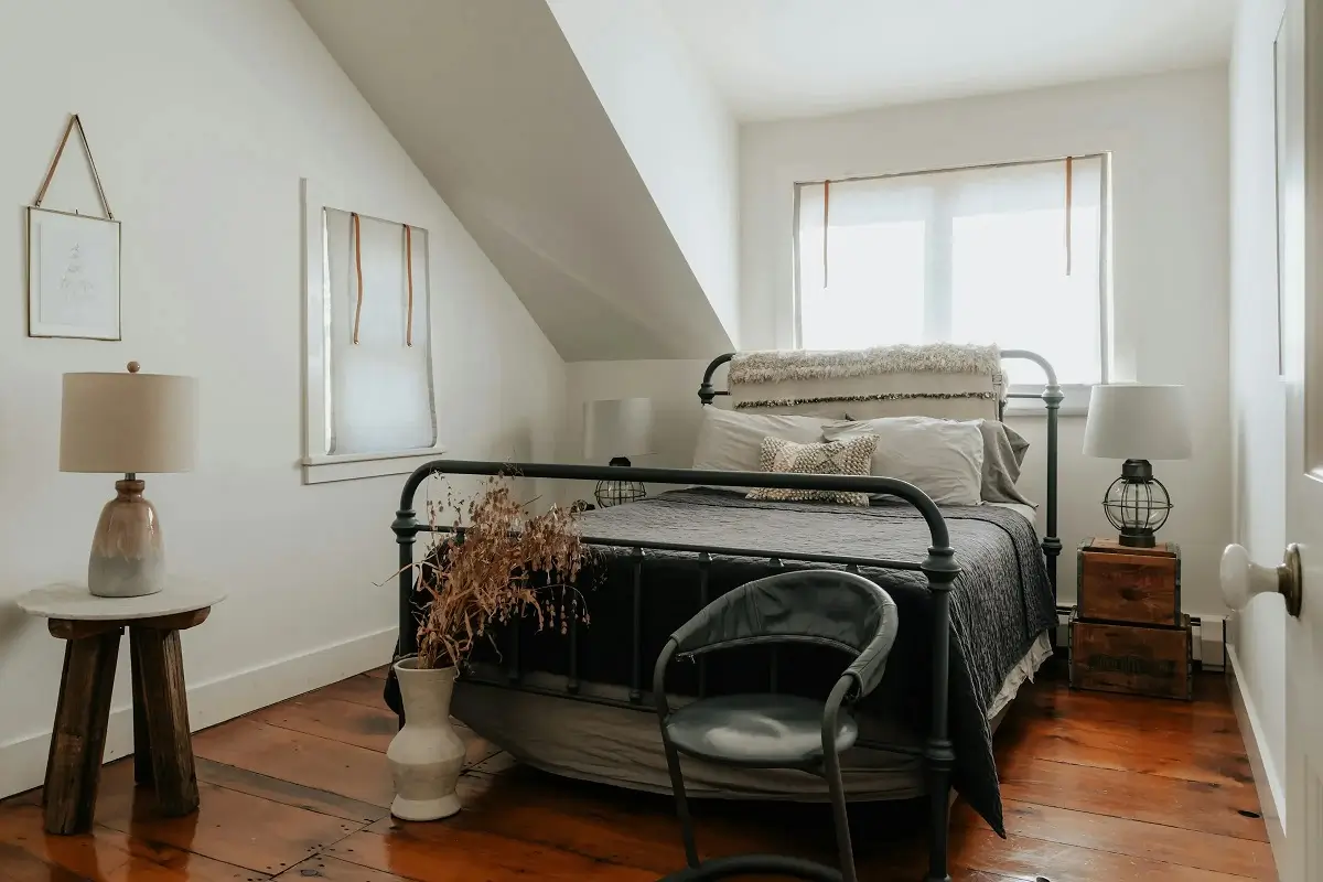 Cozy attic bedroom with iron bed frame and rustic wooden floor