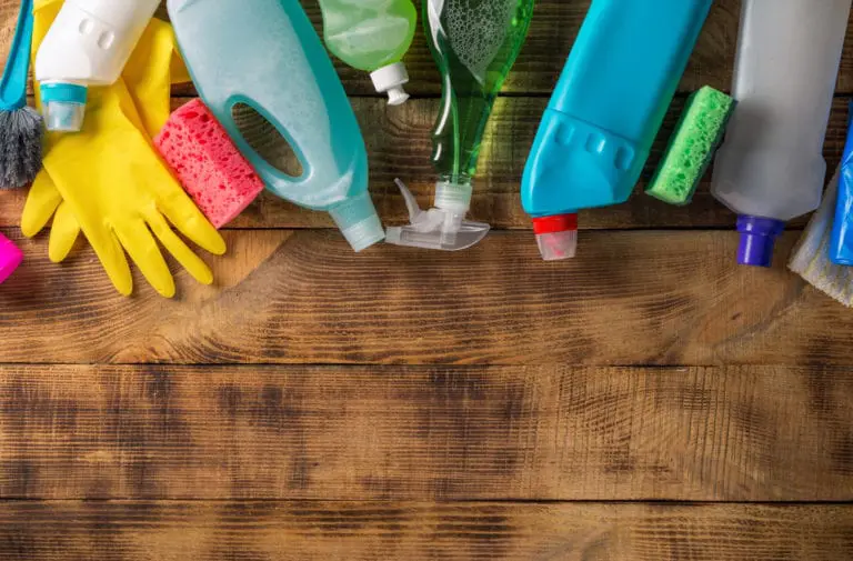 Various cleaning supplies and gloves on a wooden table