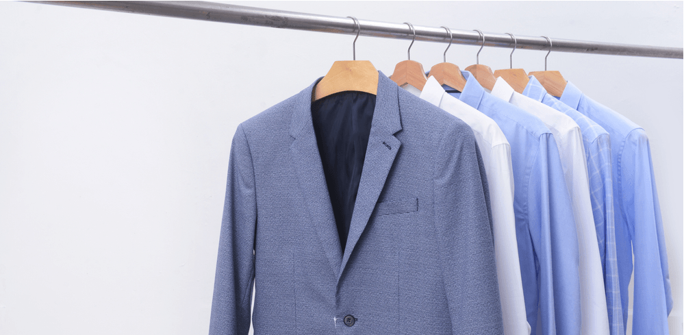 Blue suit jacket and dress shirts hanging on a clothing rack