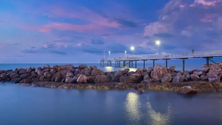 Pier over calm ocean at sunset with lights