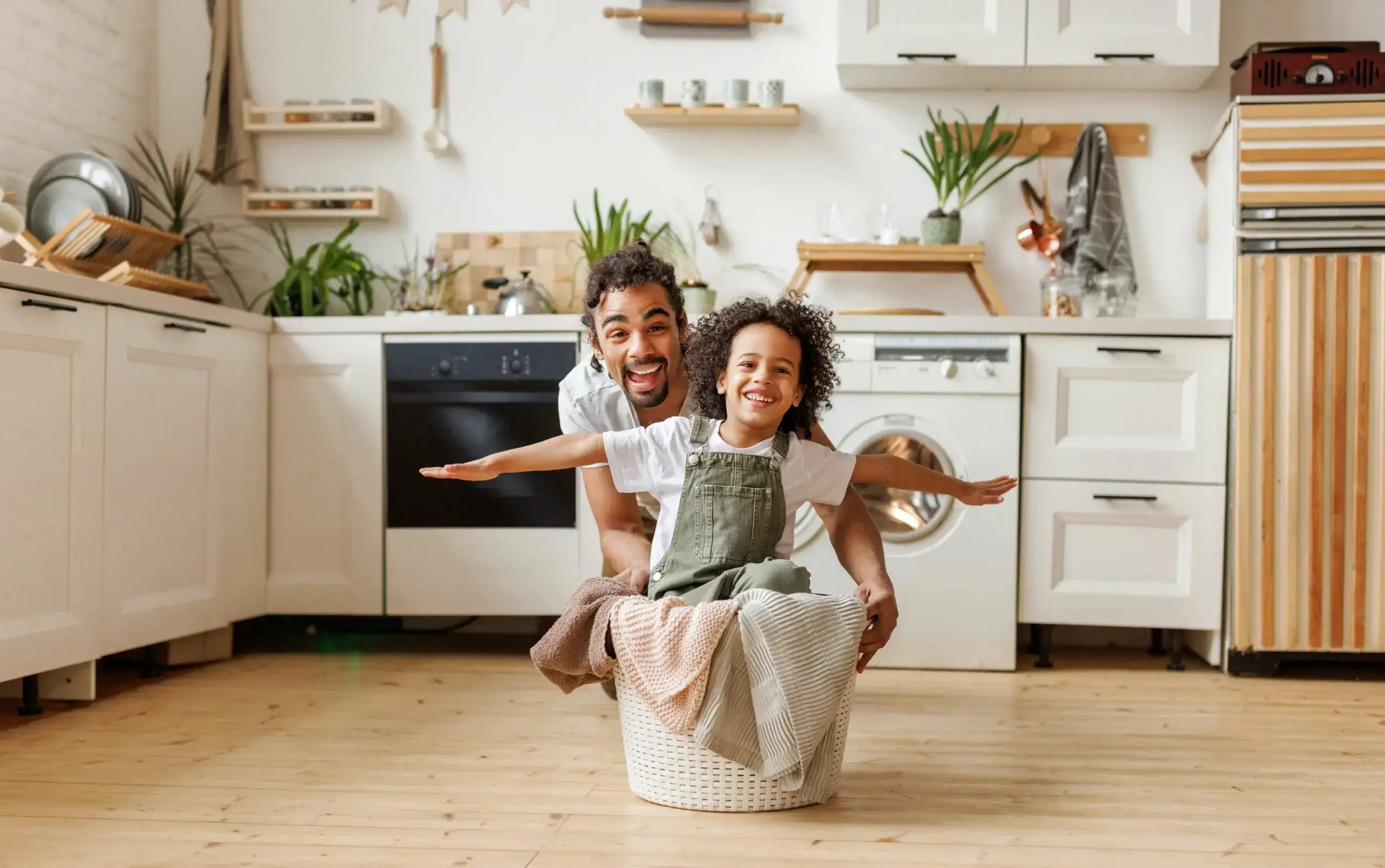 Father and child playing in laundry basket at home