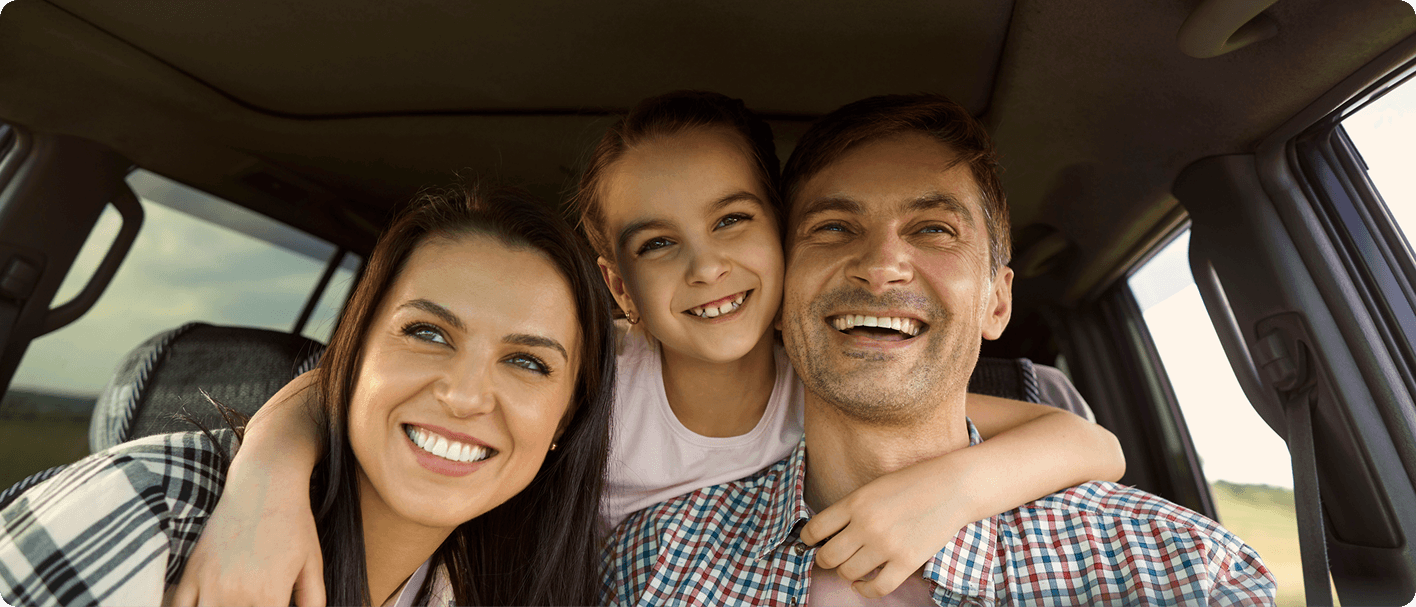 Happy family sitting in car during relocation to new home