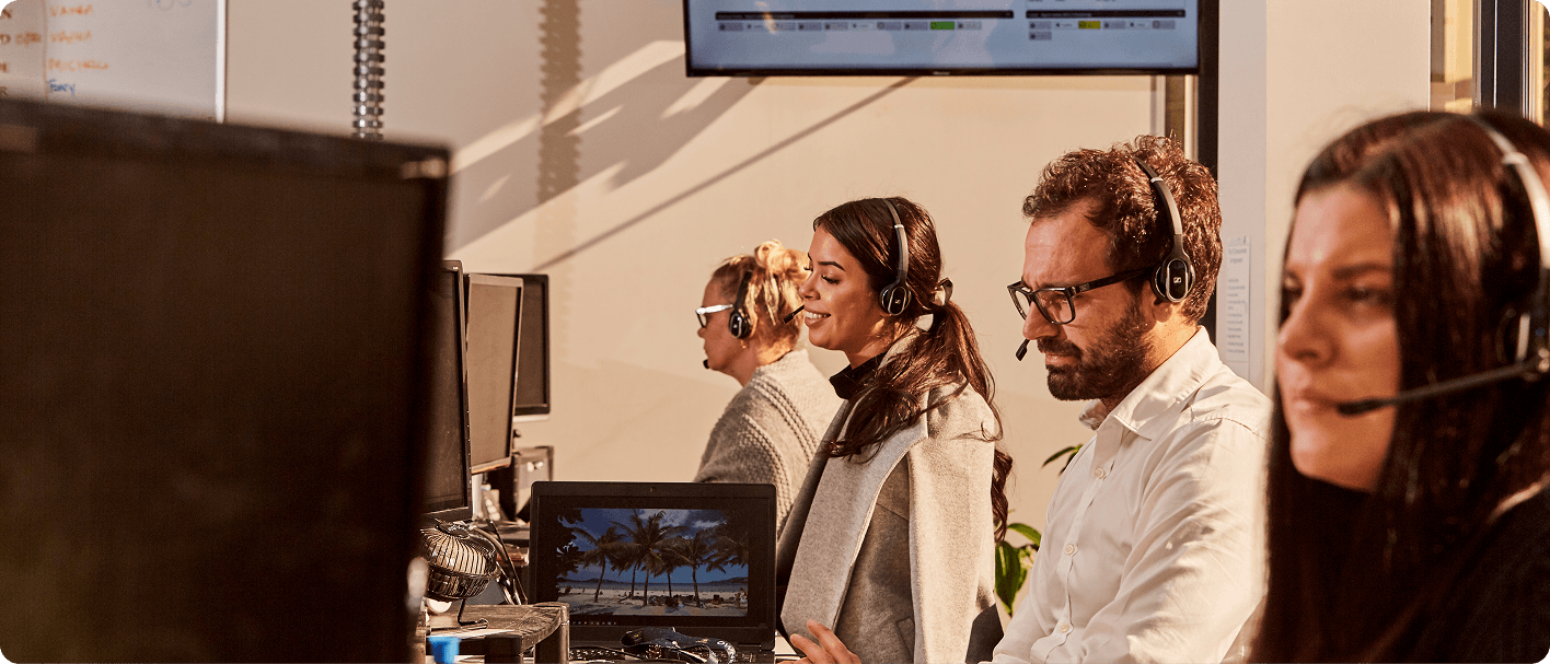 Customer service team wearing headsets working at computers in a modern office call center.