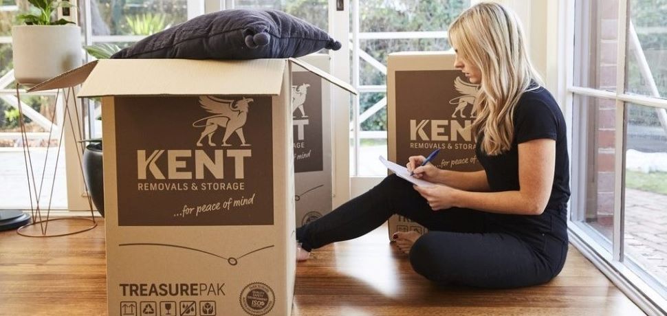 Customer sitting with Kent moving boxes and writing relocation checklist