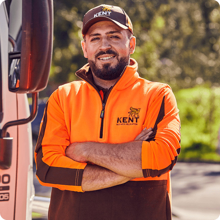 Smiling Kent Business Relocation staff member in orange uniform standing by truck
