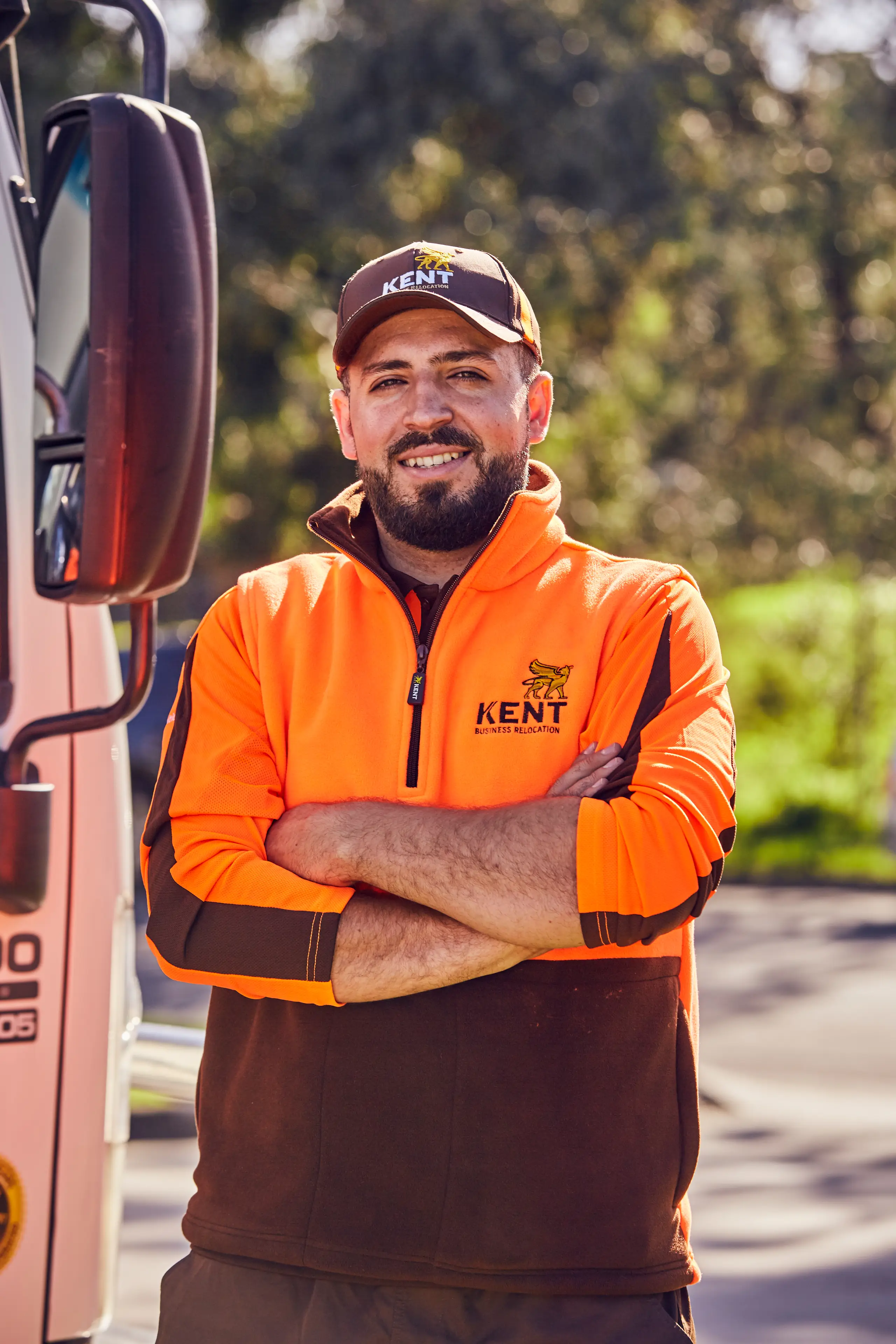 Smiling Kent Business Relocation staff member with arms crossed standing by truck